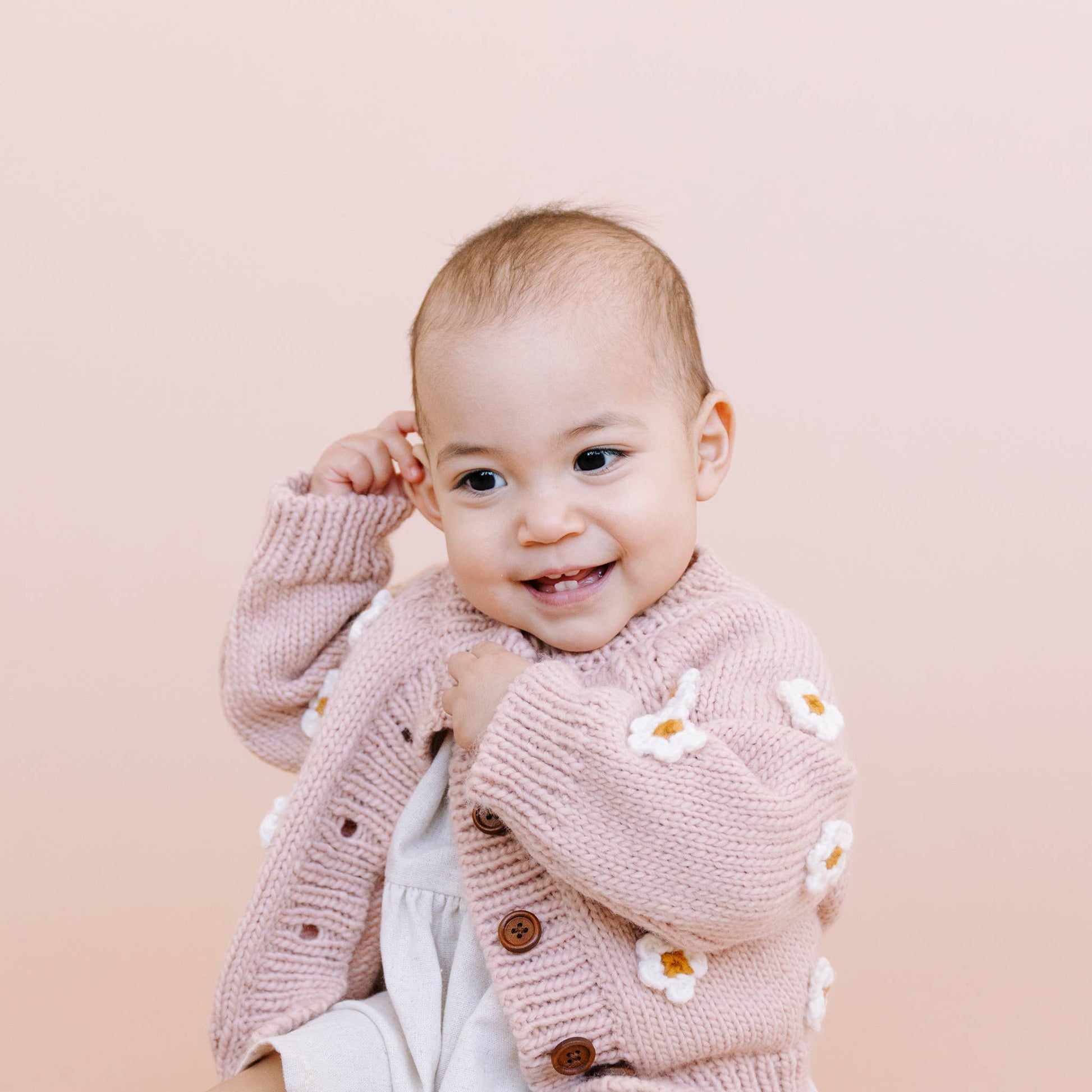 baby wearing handknit sweater with daisies