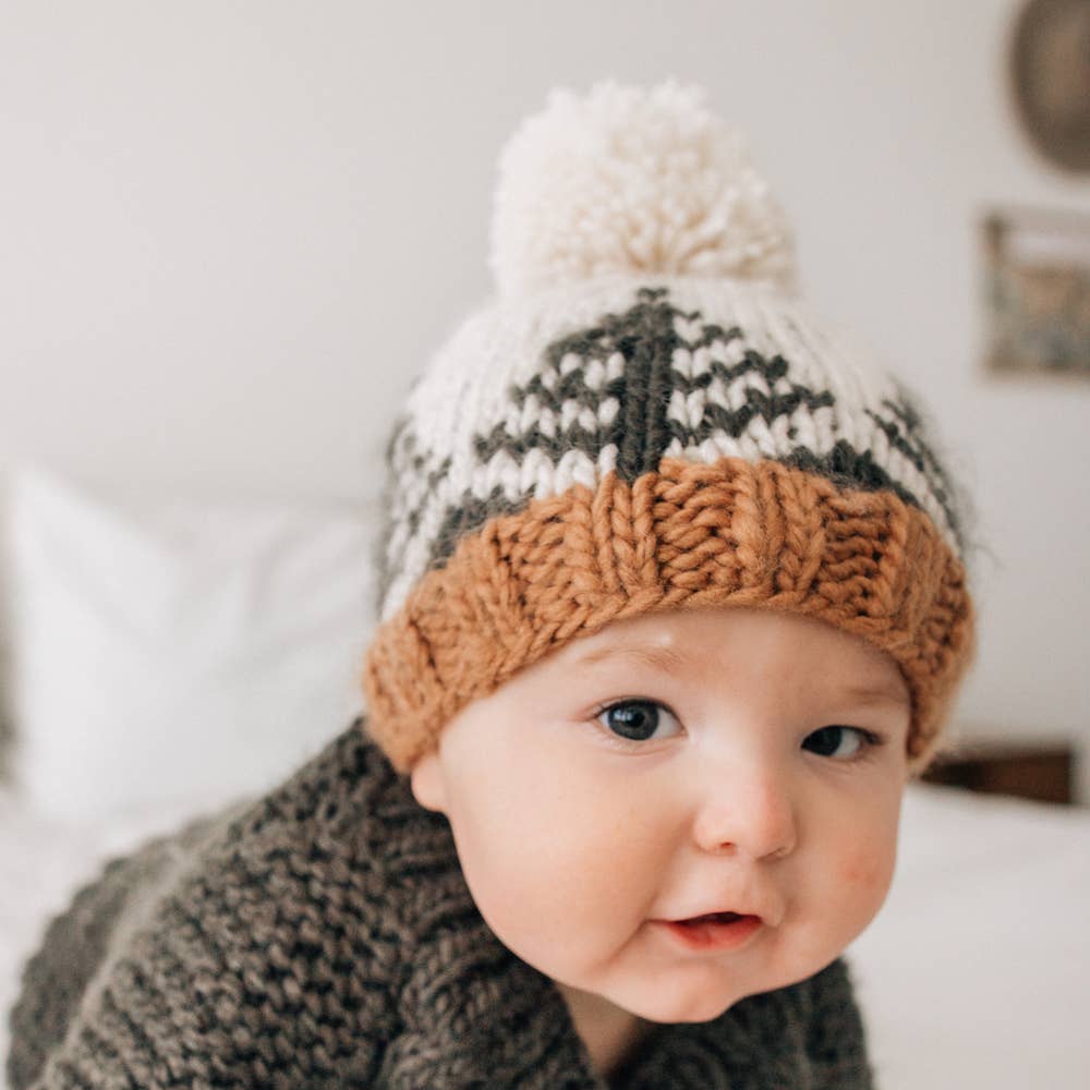 Baby in winter hat with pom pom in neutral colors 