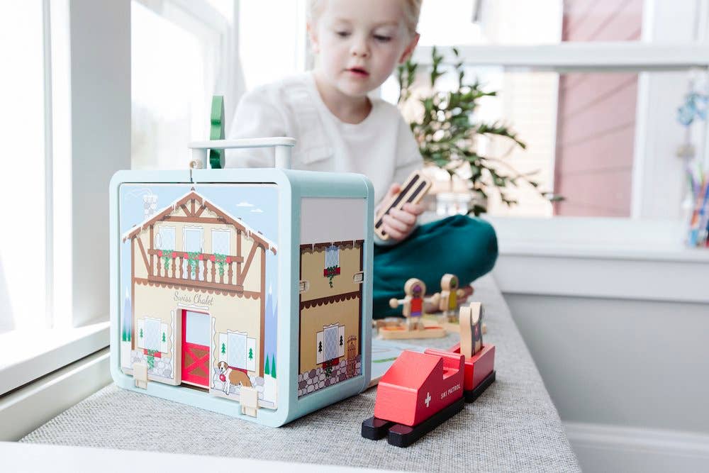 Child playing with ski chalet playset and figures